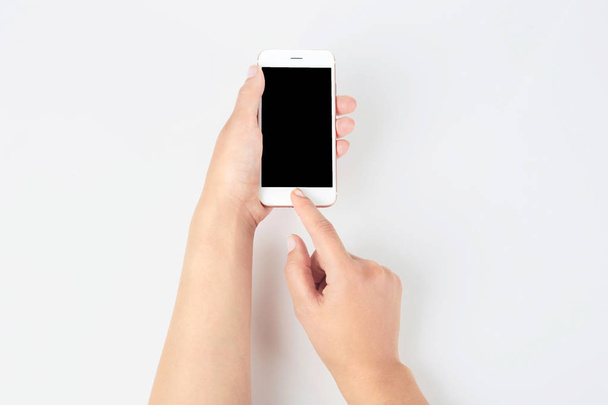 Young woman holding mobile phone with blank screen in hand on white background - Photo, Image