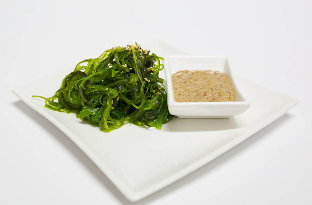 Salade de chou marin avec sauce saupoudrée de sésame dans l'assiette
. - Photo, image