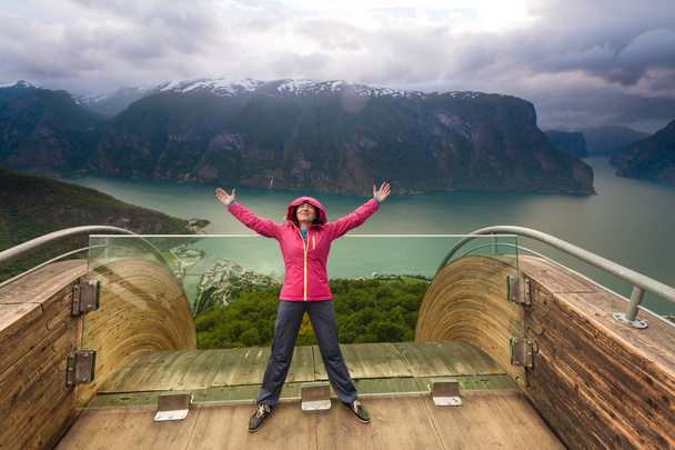 Tourist woman on Stegastein viewpoint enjoying Aurland fjord view with arms raised outstretched up, Sogn Og Fjordane, Norway - Foto, Imagem