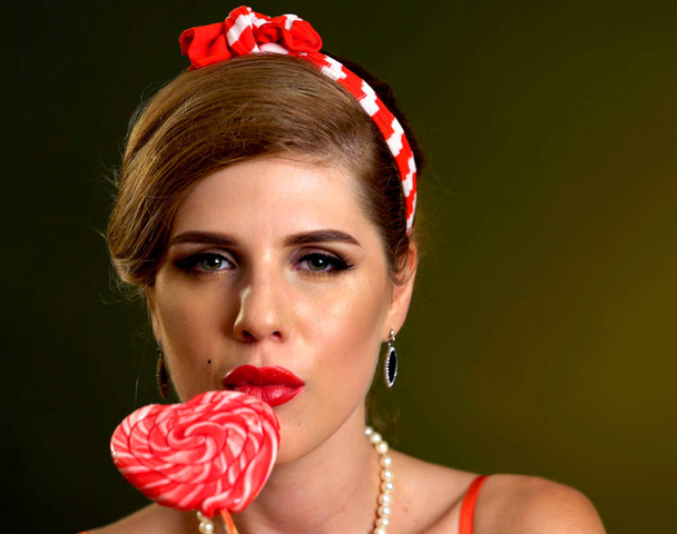 Woman eating lollipops. Girl in pin-up style hold striped candy. - Photo, image