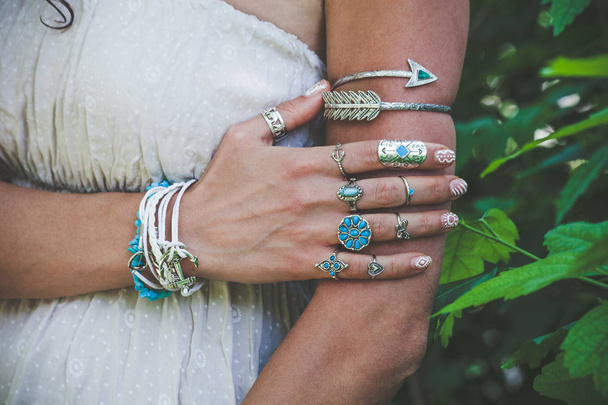 gros plan de la main et du bras de la jeune femme avec beaucoup de bijoux de style boho, anneaux et bracelets en plein air tourné jour d'été
 - Photo, image