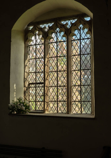 Näkymä vanhan kirkon sisältä kukkivan puun ulkopuolelle
 - Valokuva, kuva