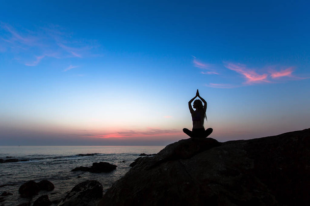 silhouette de femme de yoga sur l'océan pendant le coucher de soleil incroyable
.  - Photo, image