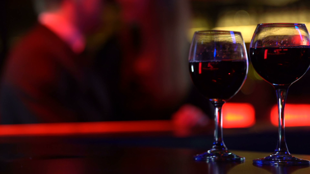 Wine glasses on bar table on happy couple background, lovers enjoying date - Footage, Video