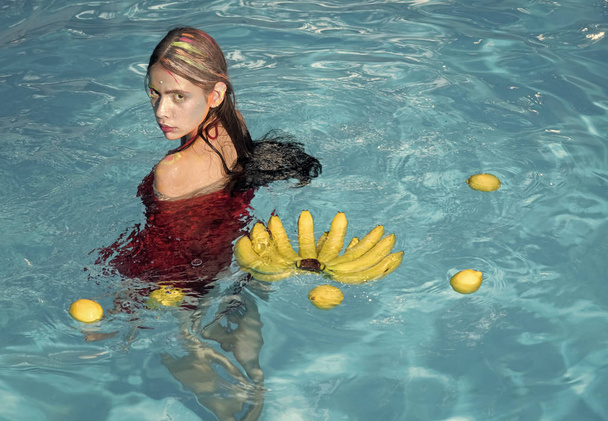 Woman face beauty. Summer vacation and travel to ocean. Vitamin in banana at girl sitting near water. Woman relax in spa pool. woman with tropical fruit in pool. Dieting and healthy organic food - Фото, изображение