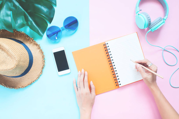 Mani laiche piatte creative con notebook e smartphone, cappello, occhiali da sole e cuffie su sfondo color pastello, concetto di vacanza estiva
 - Foto, immagini