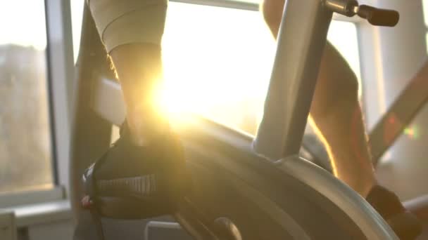 Man with injured leg riding stationary bike in morning sunlight, health recovery - Séquence, vidéo