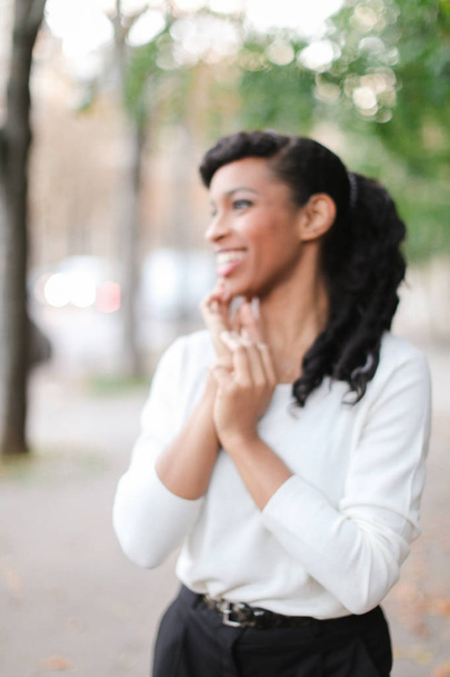 Lachende jonge zwarte vrouw dragen witte blouse en zwarte broek. - Foto, afbeelding
