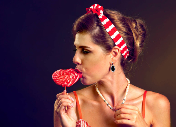 A nő evés nyalókák. Pin-up stílus lány tartsa csíkos candy. - Fotó, kép