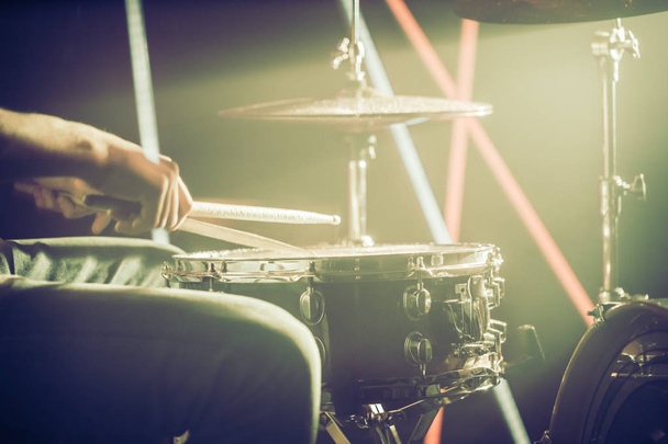 男がドラムを果たしている、ゲームはスティックのクローズ アップと作業のドラム。色のライトの背景。音楽のコンセプトと作業ドラム. - 写真・画像