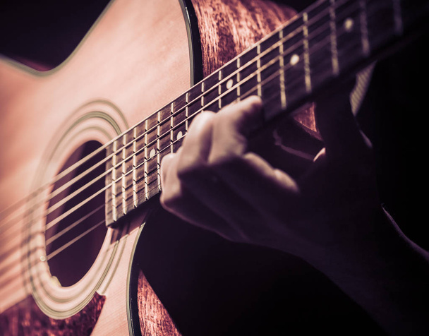 Человек, играющий на акустической гитаре на темном фоне, гитара крупным планом. Музыкальная концепция
. - Фото, изображение