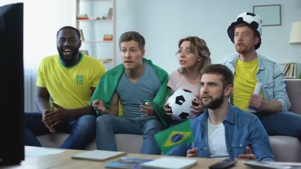 Happy Brazilian friends watching match at home celebrating goal of football team - Filmagem, Vídeo