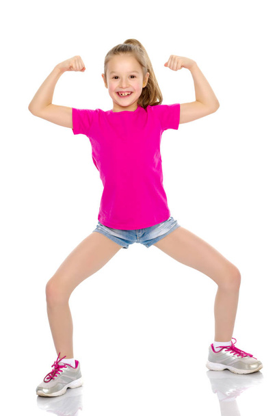 A little girl shows her muscles. - Zdjęcie, obraz