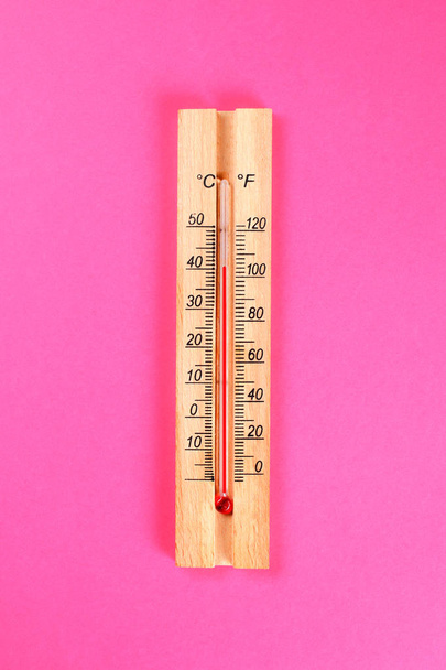 Un termómetro de madera que muestra 30-40 grados de calor sobre un fondo pastel rosado. Verano. Vista superior. Acostado. Copiar espacio
 - Foto, imagen