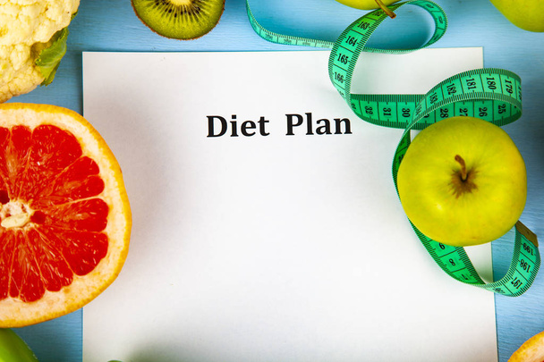 Food and sheet of paper with a diet plan on a blue wooden background. Concept of diet and healthy lifestyle. - Foto, immagini