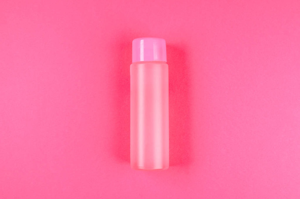 A pink bottle, a bottle for cosmetics, shampoo or food, a drink on a pink pastel background. Summer. Top view. Flat lay. Copy space - Photo, image