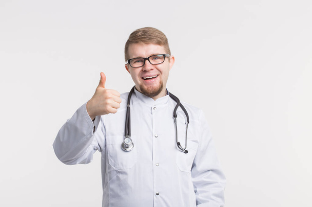 Portrait of handsome male doctor showing thumbs up over white background - Zdjęcie, obraz