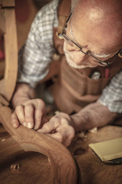 senior woodworker sanding unfinished chair - Valokuva, kuva