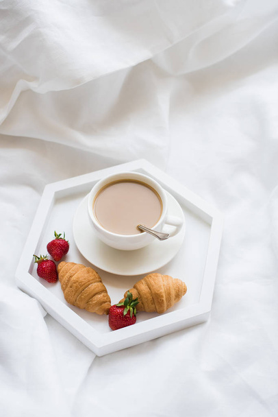Desayuno por la mañana temprano en la cama, café y croissant con fresa
 - Foto, imagen