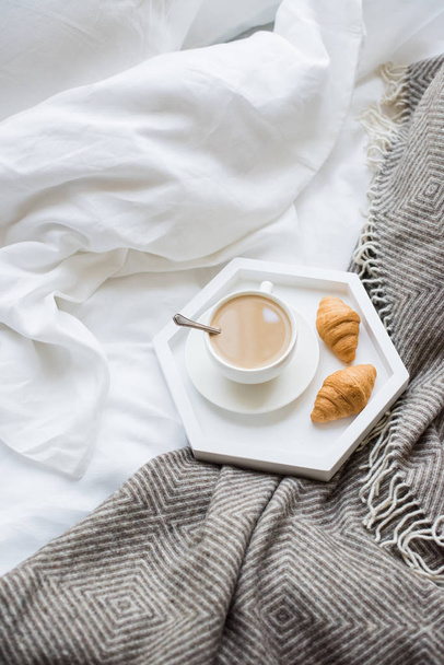 Gezellig ontbijt op bed, kopje koffie en croissants op wit en - Foto, afbeelding