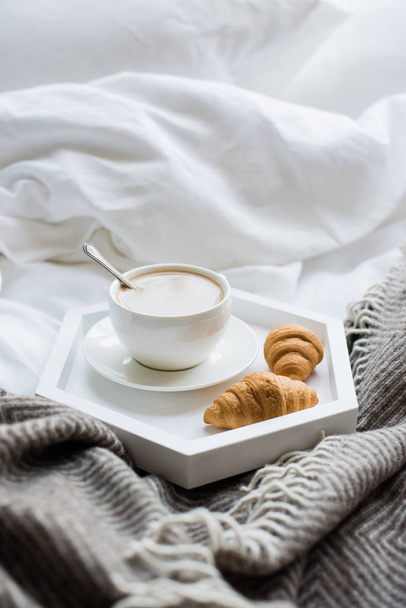 Ζεστό πρωινό στο κρεβάτι, φλιτζάνι καφέ και κρουασάν σε λευκό και - Φωτογραφία, εικόνα