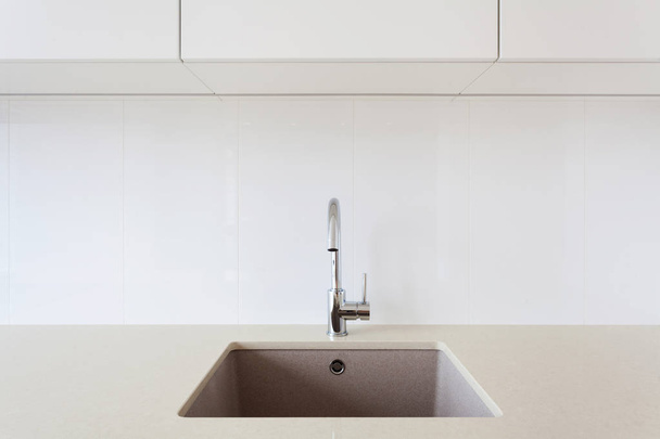 Detail of a white rectangular designer kitchen sink with chrome water tap - 写真・画像