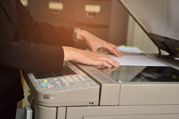 Vrouwelijke werknemers zijn het gebruik van een copier in het kantoor. - Foto, afbeelding