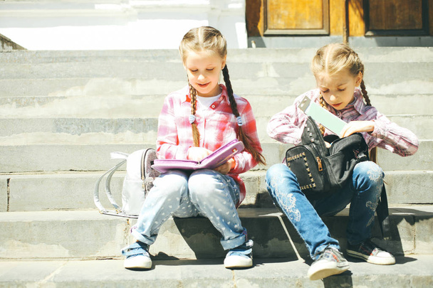Due compagni di classe seduti con le borse scolastiche sui gradini
. - Foto, immagini