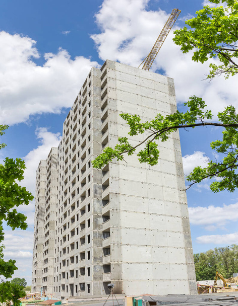 Pohled na stavbu multi příběh bytového domu z betonových prefabrikátů celé větve stromů - Fotografie, Obrázek