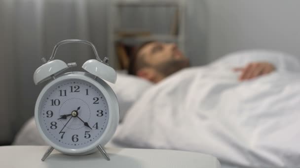 Man in bed waking up to ringing alarm clock, healthy lifestyle, discipline - Video, Çekim