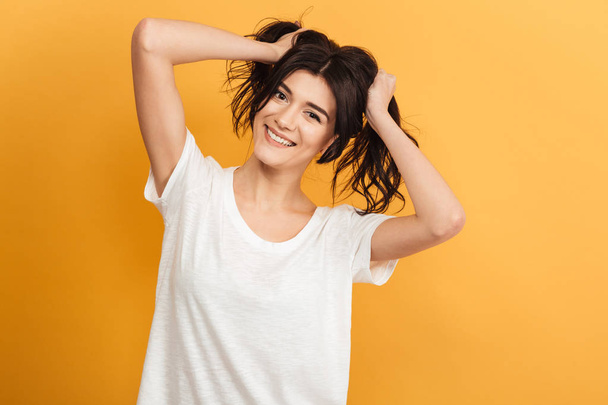 Image of happy funny young pretty woman standing isolated over yellow background looking camera. - Foto, Bild