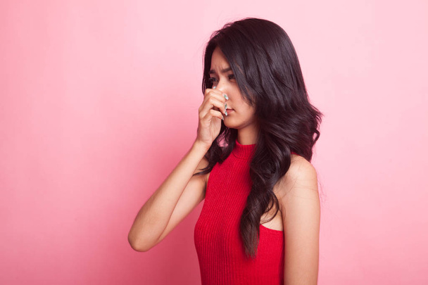 Mladá asijská žena drží nos, protože špatný zápach na růžovém pozadí - Fotografie, Obrázek