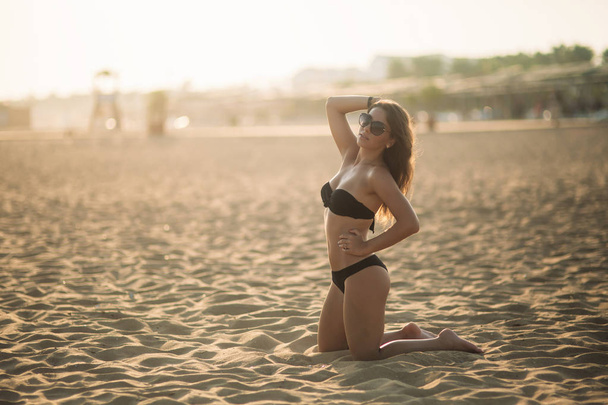 Sexy lady in bikini sunbathing on a sandy beach - 写真・画像