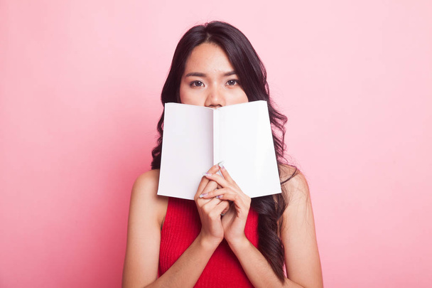 Young Asian woman with a book on pink background - Foto, Imagen