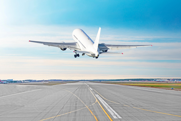 De vliegende vertrek vliegtuig opstijgen op een start-en landingsbaan luchthaven mooi weer met een blauwe hemel wolken op een baan. Achteraanzicht. - Foto, afbeelding