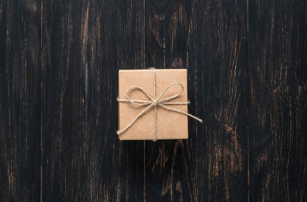 gift box tied with string on a dark wooden background - Foto, afbeelding