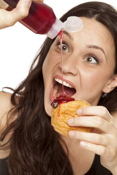 Прожорливая молодая женщина кладет вишню на пончик на белом фоне
 - Фото, изображение