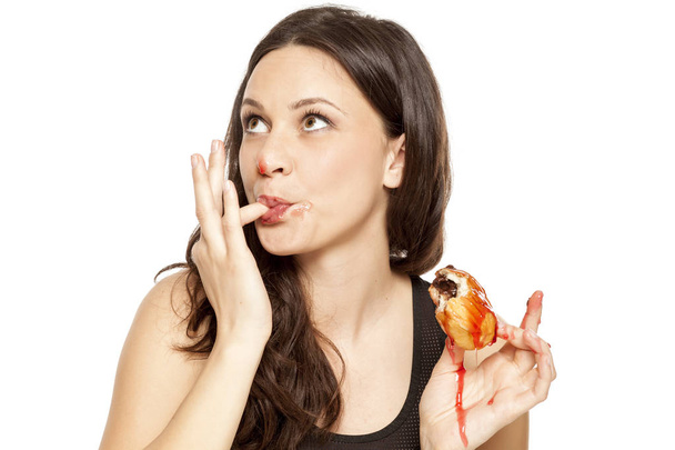 Hunkeren naar van jongedame eten een kers topping donut op een witte achtergrond - Foto, afbeelding