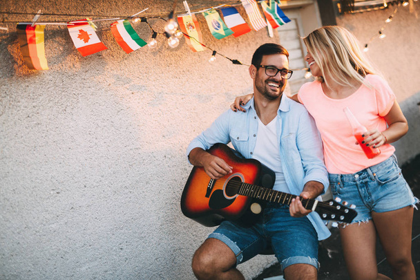 Young man playing guitar for friends and his pretty girlfriend - Fotoğraf, Görsel