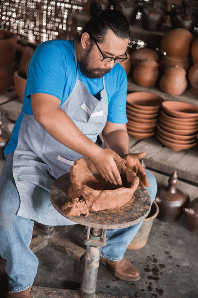 happy pottery maker creating a beautiful ceramic vase in his workshop - Foto, Imagen