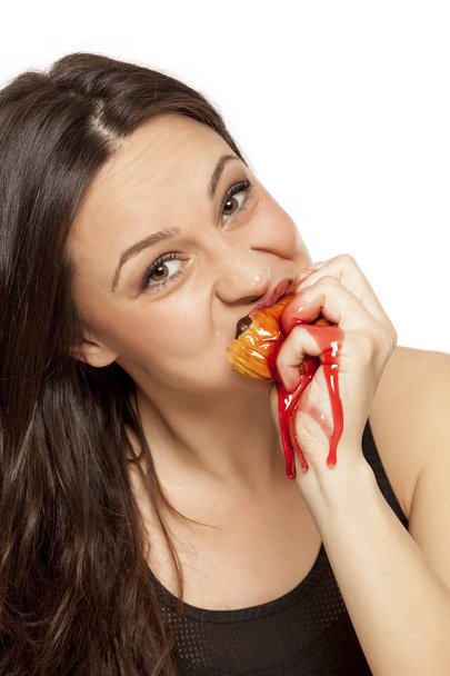 Craving young woman eating a cherry topping donut on a white background - Photo, Image