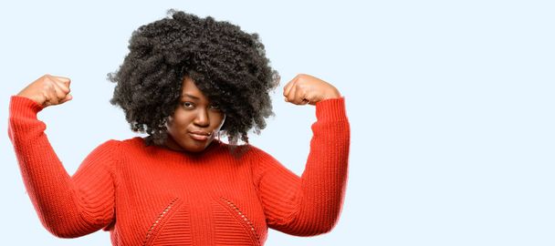 Belle femme africaine montrant biceps exprimant la force et le concept de gymnase, vie saine son bon, fond bleu
 - Photo, image