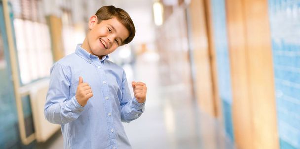 ハンサムな幼児児緑目幸せと興奮祝う勝利大成功、力、エネルギーおよび肯定的な感情を表現します。学校の廊下でうれしそうな新しい仕事を祝う - 写真・画像