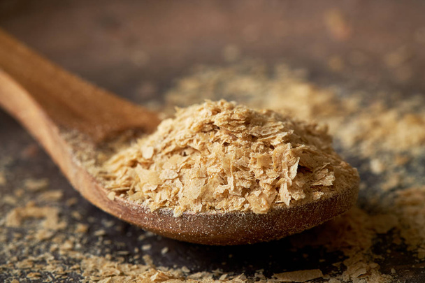 Close-up van nutritionele brouwers gist vlokken in houten lepel - Foto, afbeelding