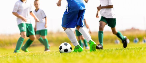 Fiatal fiúk rúgás labdarúgó mérkőzés a füves pályán. Ifjúsági sport verseny között fehér és kék a labdarúgó-válogatott - Fotó, kép