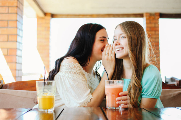 Két gyönyörű lányok isznak friss gyümölcs smoothies egy kávézóban. - Fotó, kép