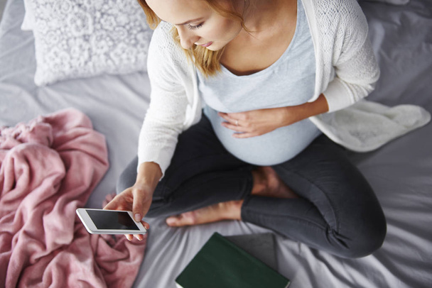 Schwangere benutzt Handy im Schlafzimmer  - Foto, Bild