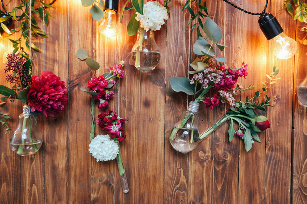 Rustic wedding photo zone. Hand made wedding decorations includes Photo Booth  red flowers. Garlands and light bulbs - Photo, image