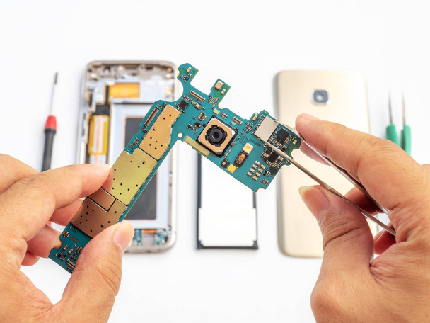 Close-up de técnico segurando placa lógica do smartphone e microprocessador de fixação no fundo componente de smartphone desfocado
 - Foto, Imagem