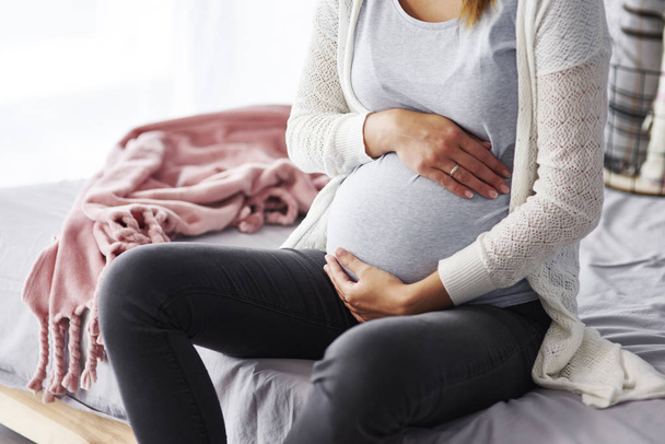 Mulher grávida irreconhecível tocando seu estômago
 - Foto, Imagem